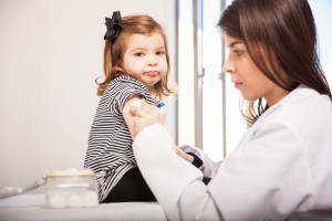 Portrait of a cute little girl looking scared while her doctor prepares her for a vaccination